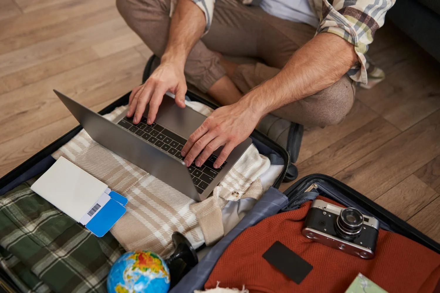 Una persona mirando su computador mientras revisa una reserva de viaje en un aeropuerto para prevenir los ciberataques a viajeros