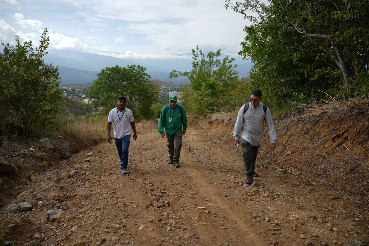 Un sendero ecológico en Antioquia rodeado de vegetación seca donde los viajeros caminan con responsabilidad para prevenir incendios forestales.
