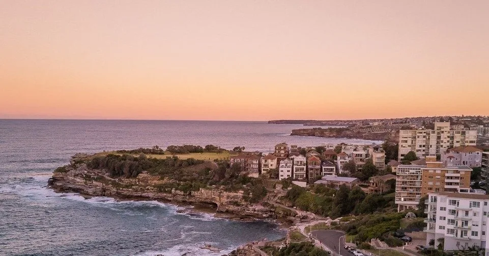 Vista panorámica de una costa rocosa e iluminada por la luz cálida del atardecer con el océano de fondo